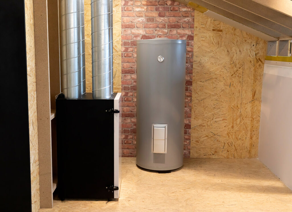 A grey electric storage water heater in an unfinished house.